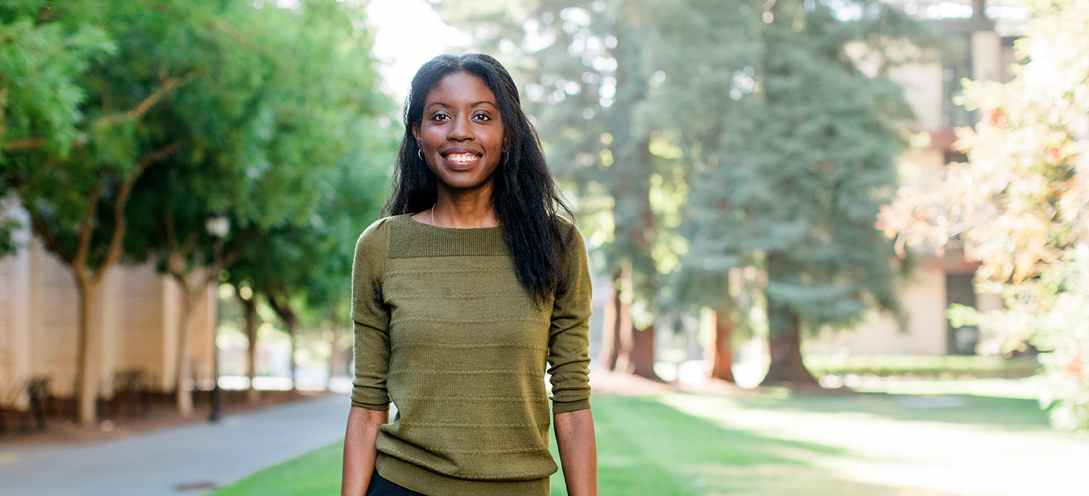 Leah Guthrie, waist up, standing on a lawn in front of trees. She is wearing a green sweater and black pants.