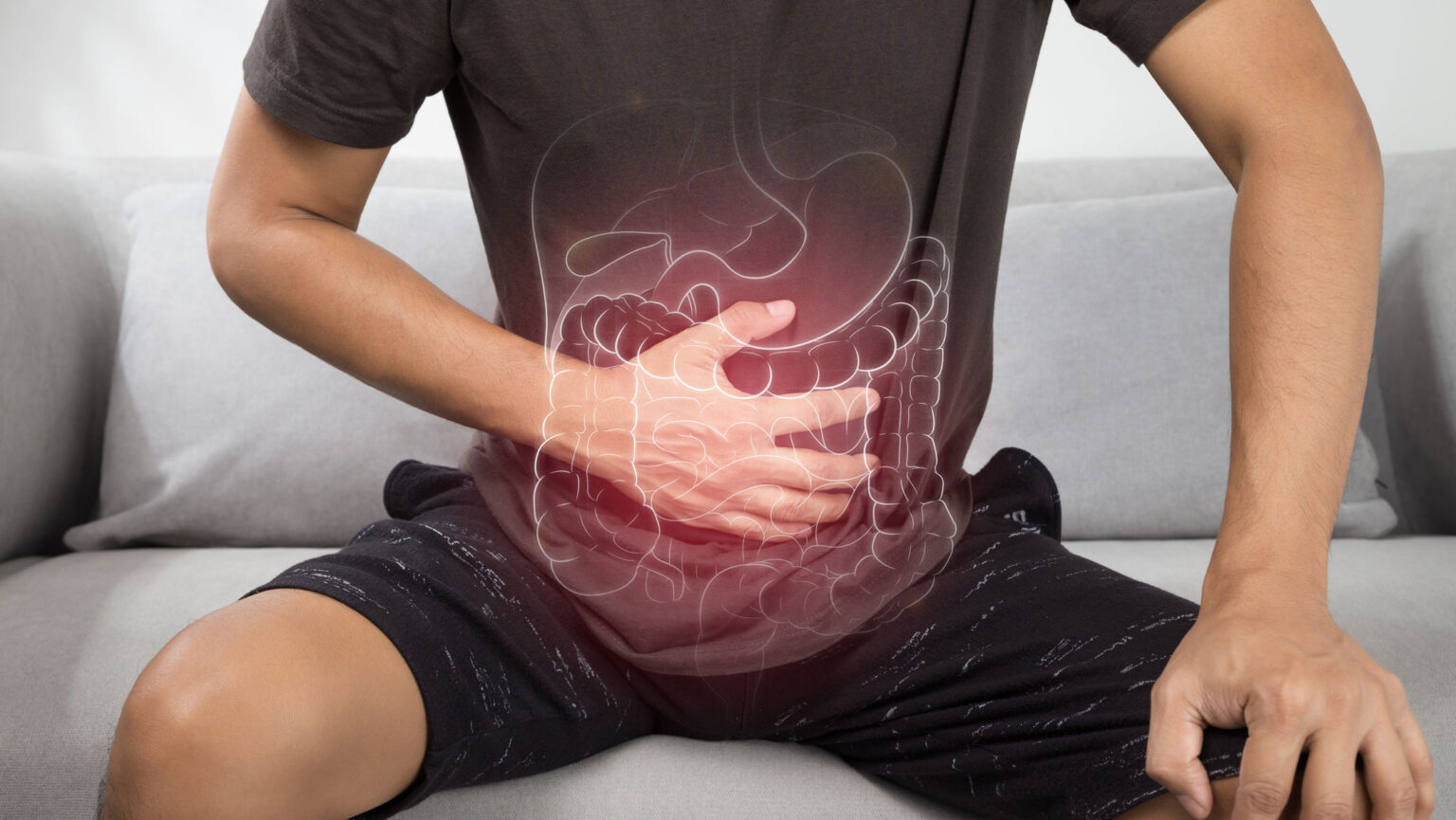 Photo of person with hand on stomach, drawing of digestive system superimposed on top. Image by iStock.