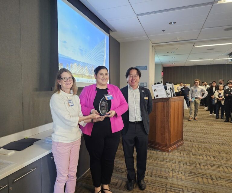 photo of Kapil standing with her award with two faculty members