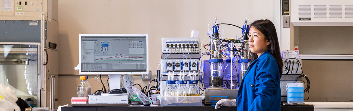 photo of alumnus Tammy in front of lab bench at her startup