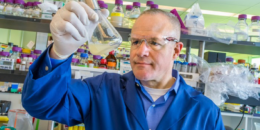 head and shoulders photo of Keasling in lab examining a flask of fluid. photo by JBEI