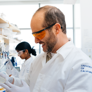 photo of Dueber in lab coat working at lab bench