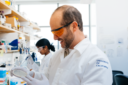 photo of Dueber in lab coat working at lab bench