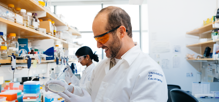 photo of Dueber in lab coat working at lab bench