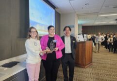 photo of Kapil standing with her award with two faculty members