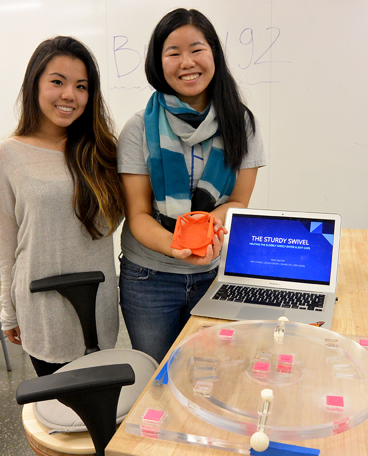 two female students displaying their prototype class project and slide on a laptop