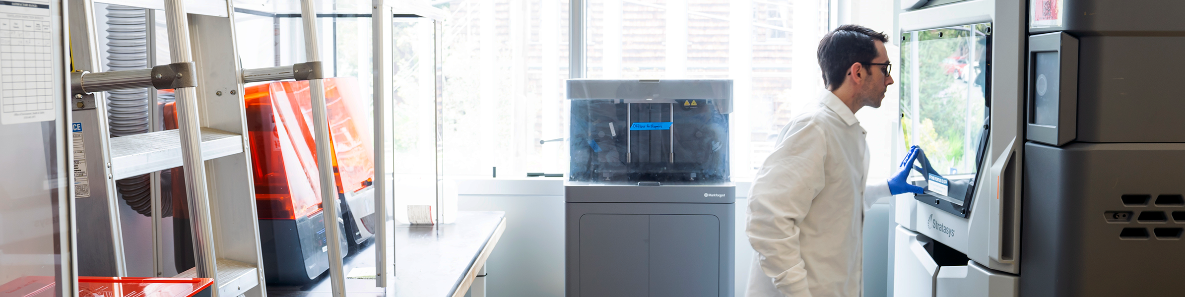 photo of student in lab coat monitoring a 3D print in Jacobs Hall