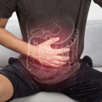 Photo of person with hand on stomach, drawing of digestive system superimposed on top. Image by iStock.