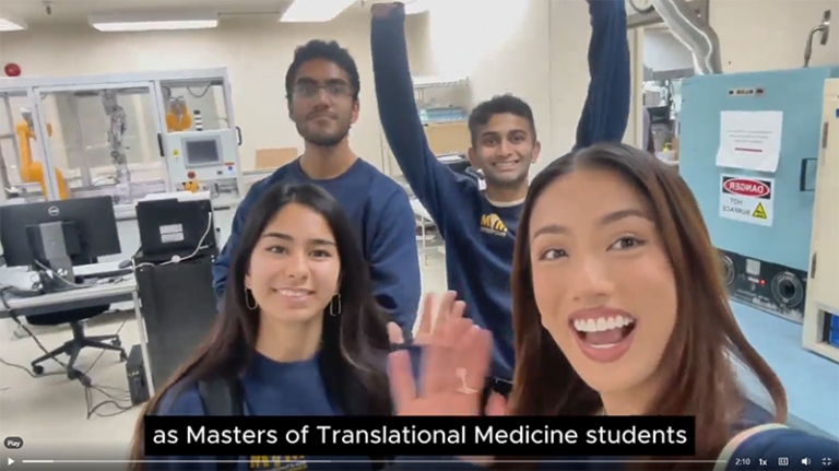 still frame from video of four MTM students waving in laboratory